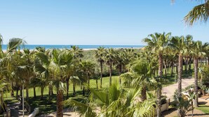 A tropical resort with palm trees, a pathway, and a view of the ocean. - Apartamentos Playamarina (Ayamonte)