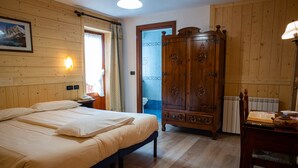 A bedroom with a large bed, wooden wardrobe, and a nightstand. - Hotel Santa San (Ayas)