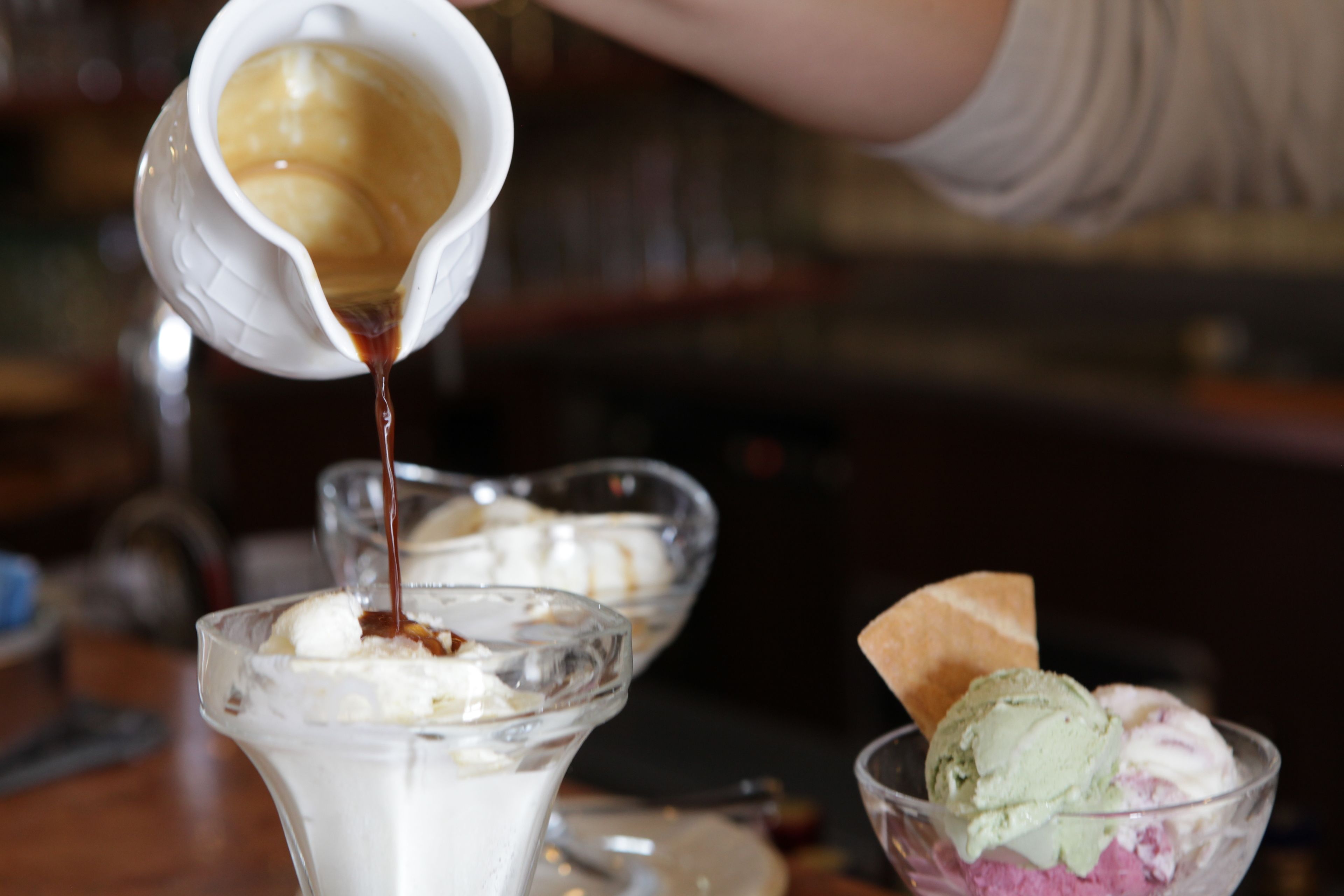 Ein Dessert wird zubereitet, eine cremige Soße wird darüber gegossen.