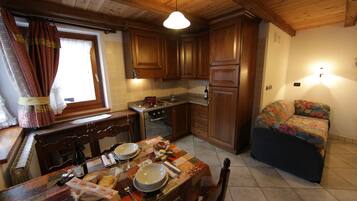 Una cocina compacta con armarios de madera, una mesa de comedor para dos personas y un sofá en la esquina.