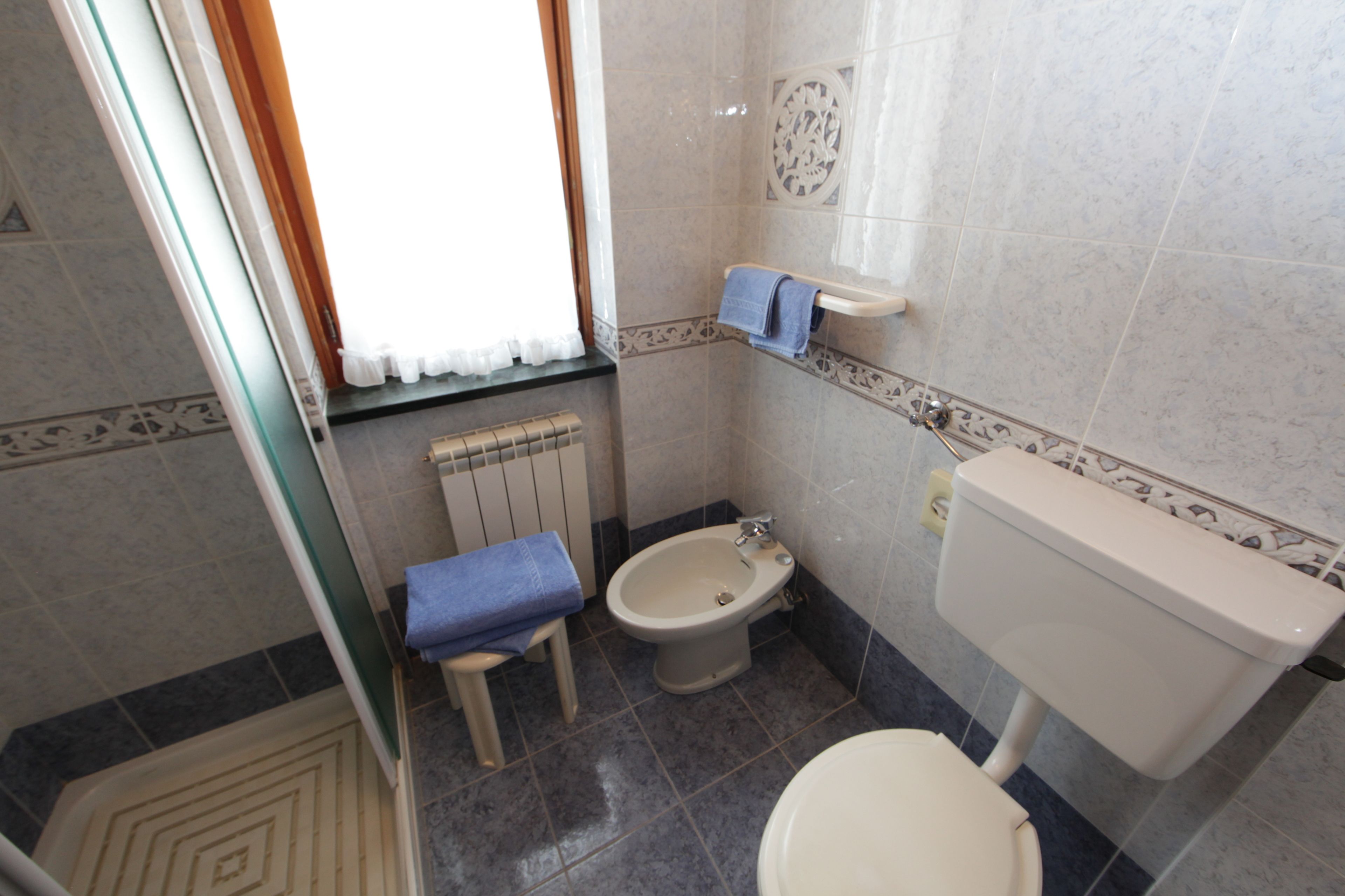 A small bathroom with a toilet, bidet, and a small sink.