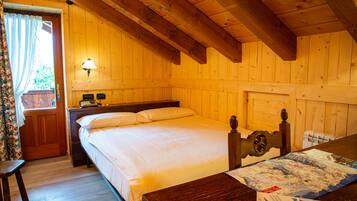Une chambre dans un chalet en bois, avec un lit, une table de chevet, une lampe et une table sur laquelle est posée une carte.
