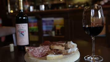 Uma mesa redonda de madeira com um copo de vinho tinto e uma garrafa de vinho.