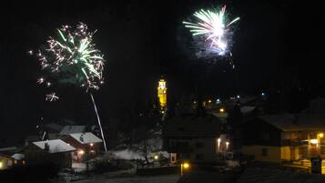 A nighttime scene with fireworks and a lit tower in the background.