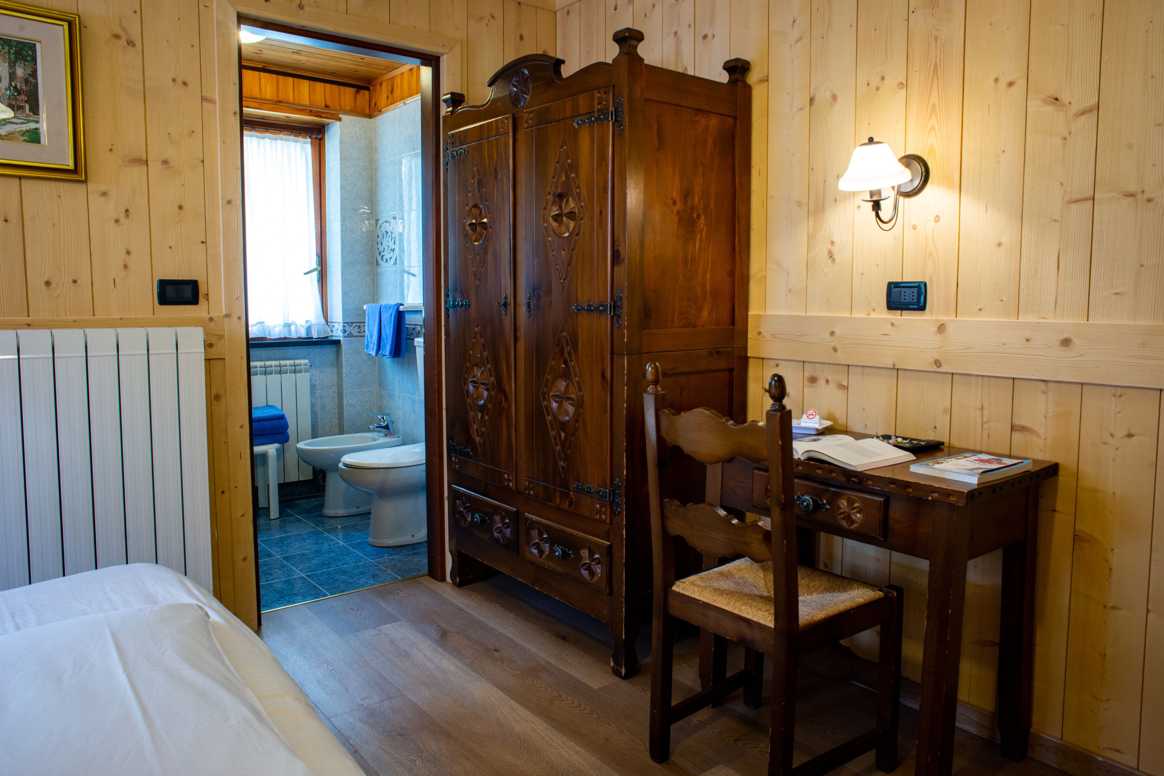 Una stanza con rivestimento in legno, un letto, una scrivania, una sedia e un armadio.