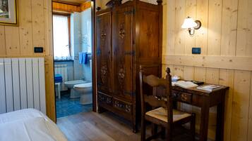 Una stanza con rivestimento in legno, un letto, una scrivania, una sedia e un armadio.