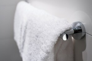 Toalha branca pendurada em um porta-toalhas de cromo em um banheiro.