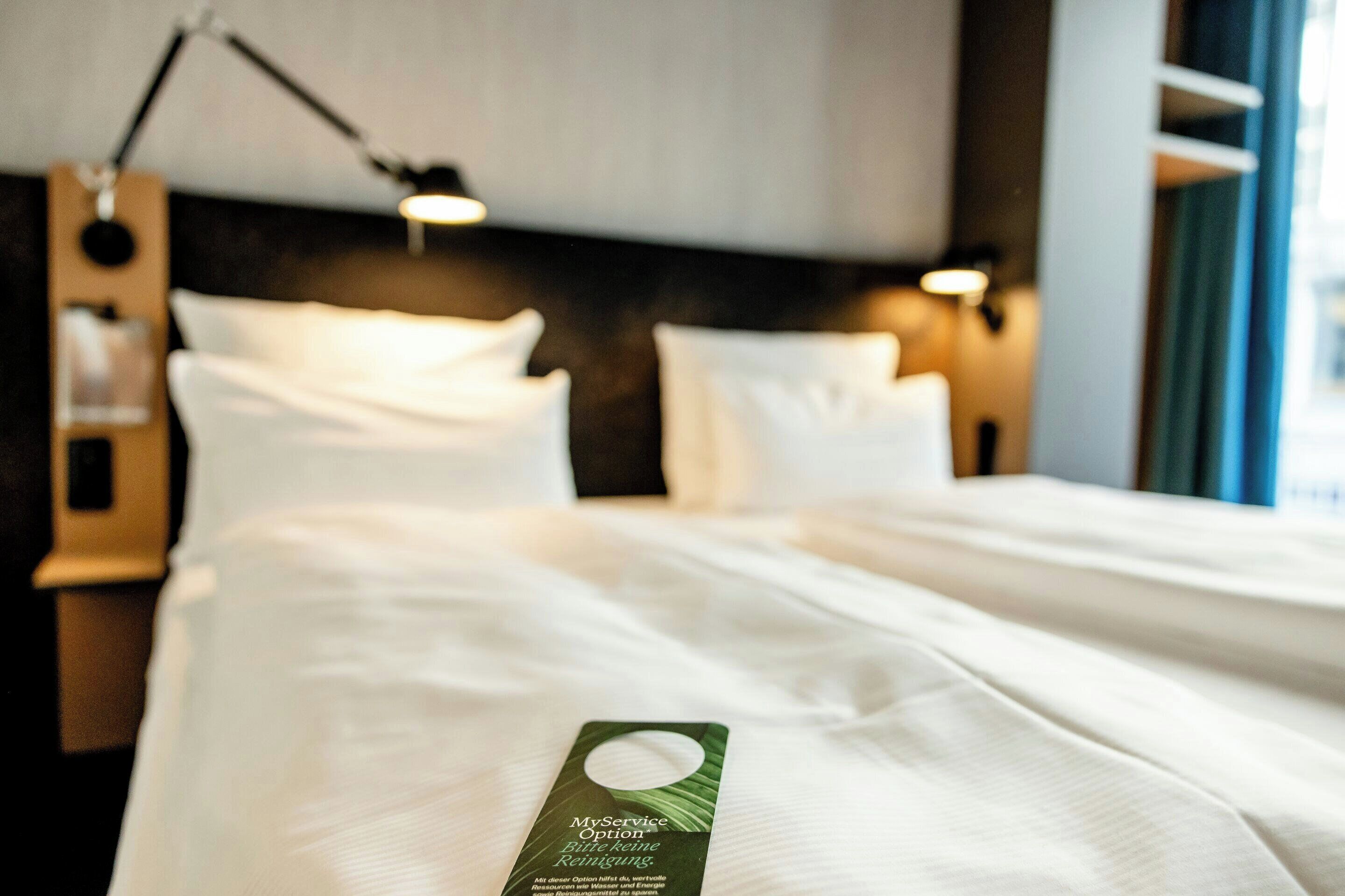 Una cama bien hecha con sábanas blancas y una etiqueta verde sobre el edredón.