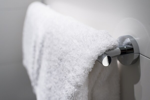 Une serviette blanche est suspendue à une barre à serviettes métallique dans une salle de bain.