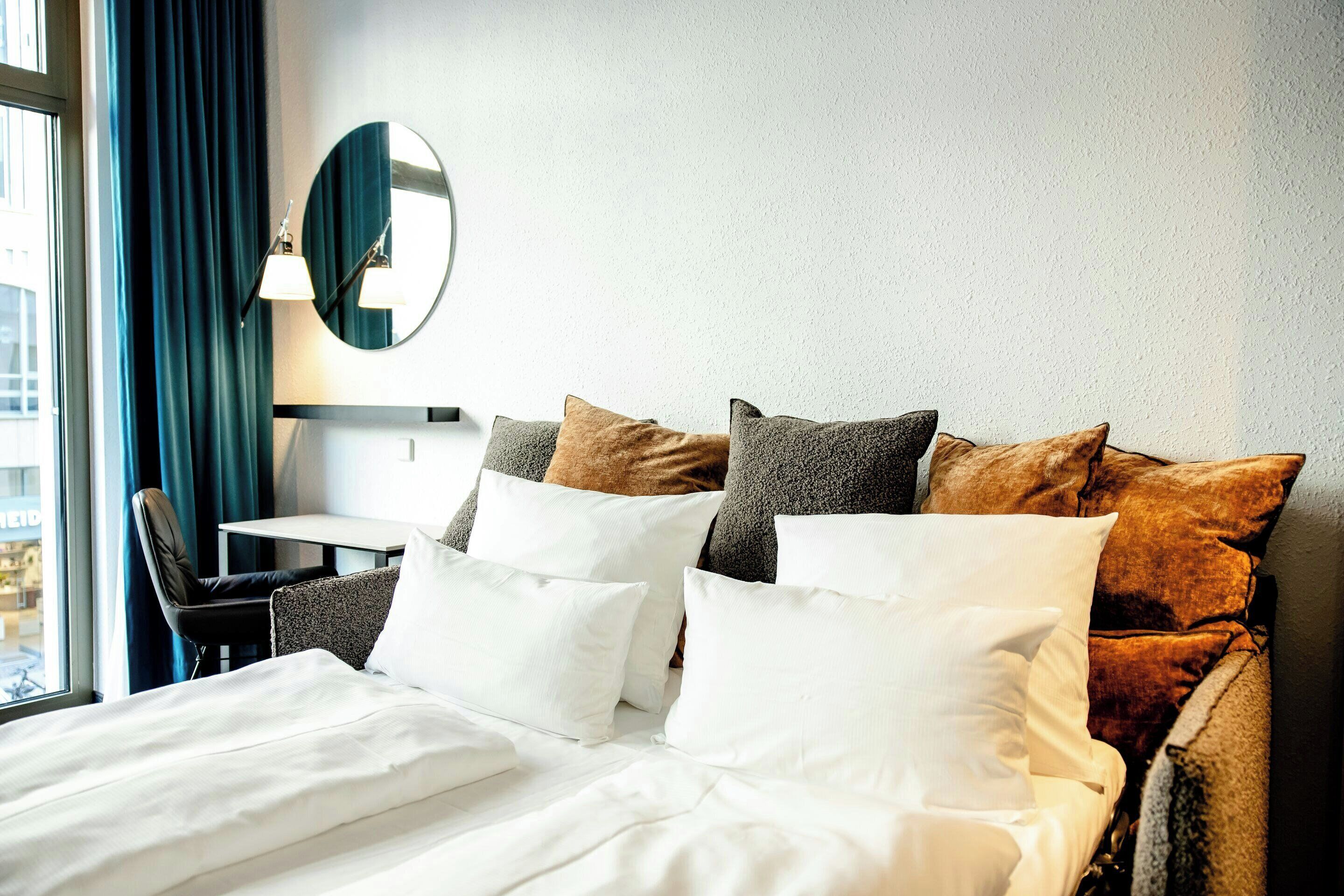 A hotel room with a neatly made bed, a desk, and a chair.