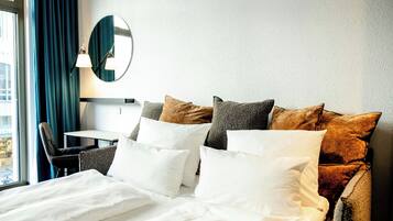 A hotel room with a neatly made bed, a desk, and a chair.