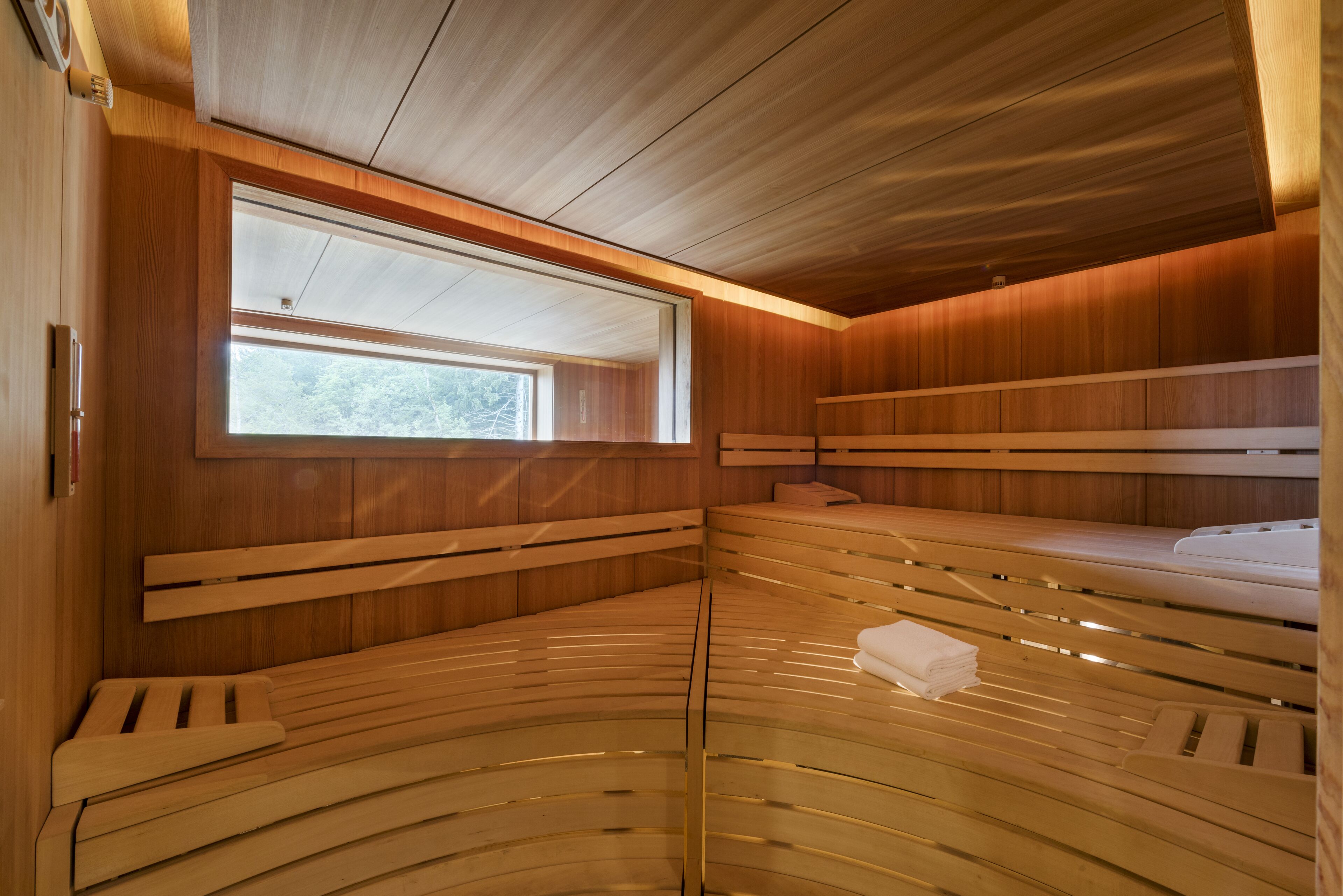 A wooden interior with a window, benches, and a towel on one of the benches.