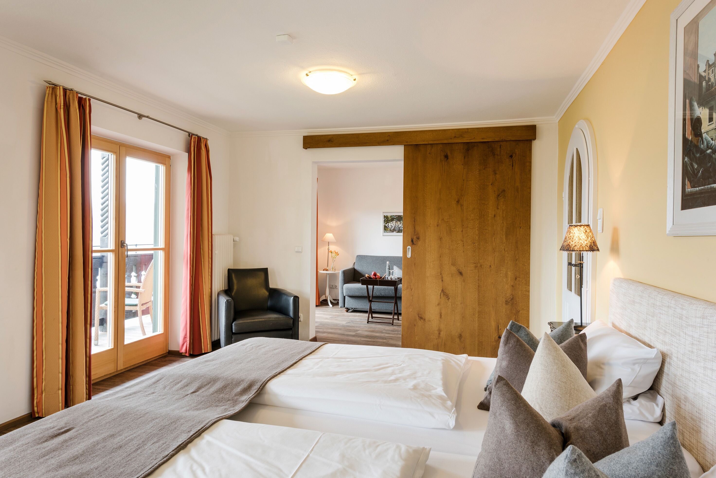 Habitación de hotel con dos camas, una puerta de madera, un sofá y una mesa de comedor.