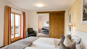 Habitación de hotel con dos camas, una puerta de madera, un sofá y una mesa de comedor.