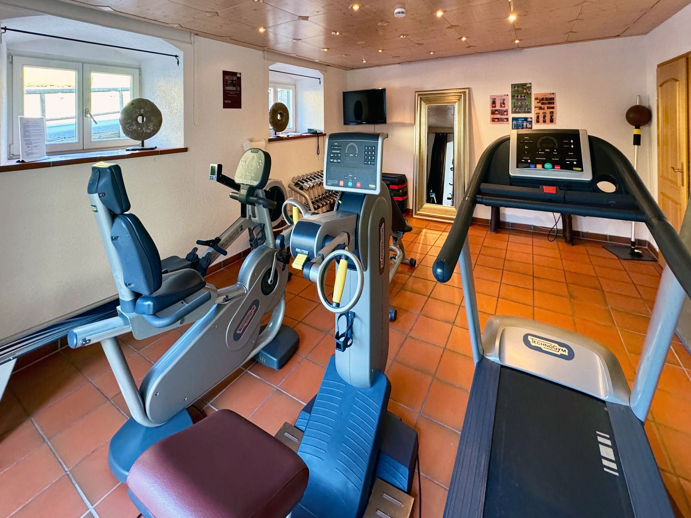 Un gimnasio con máquinas de cardio, una cinta de correr y equipo de ejercicio.