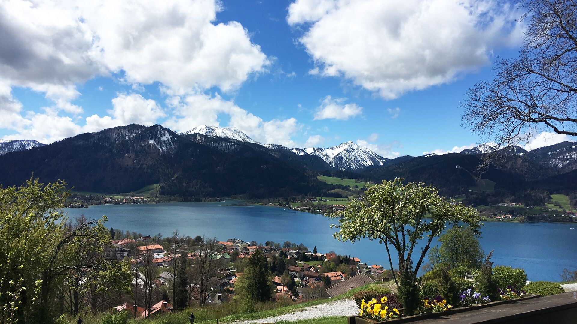 A lake surrounded by mountains and a small town with houses and trees.