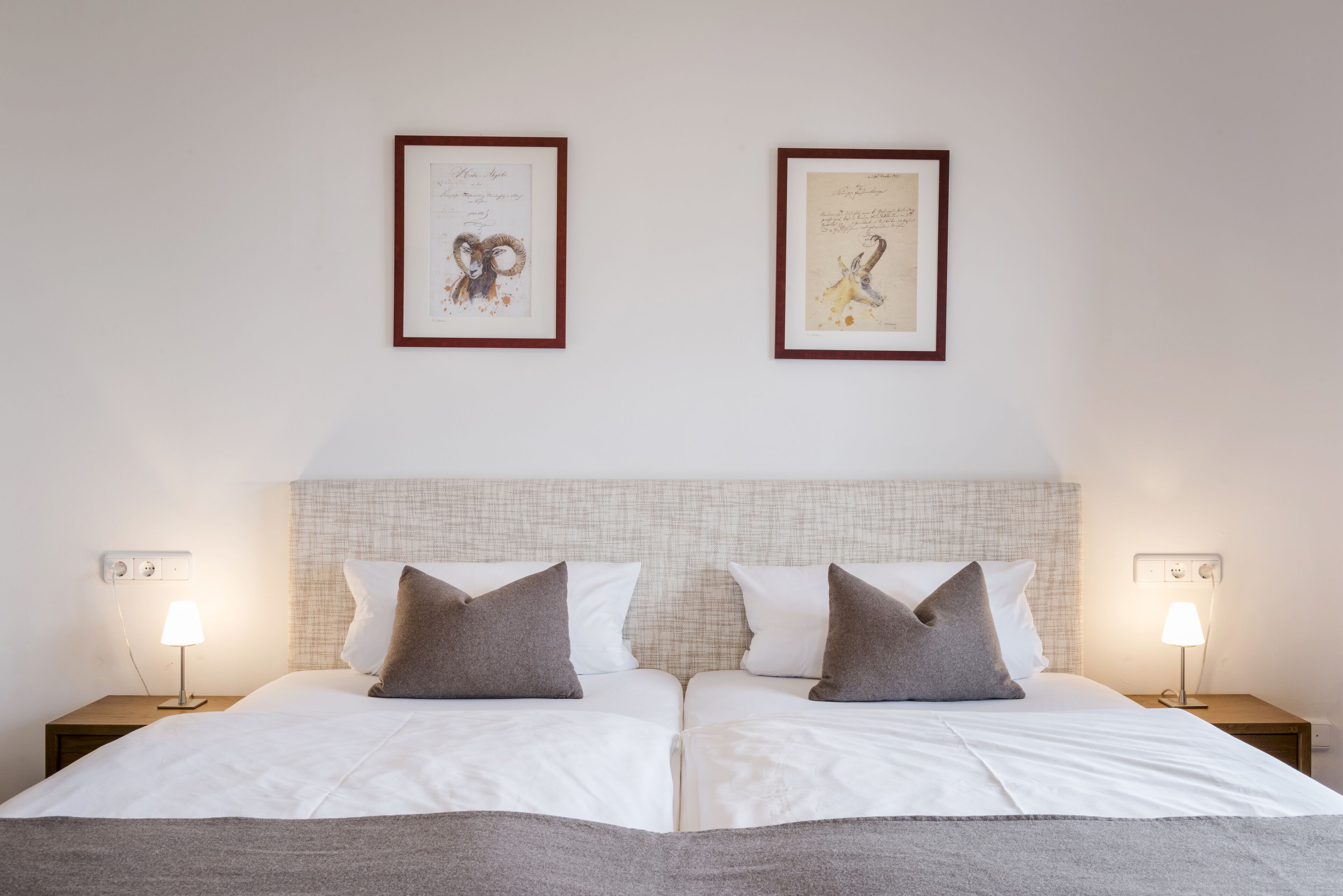 En dobbeltseng med to sengeborde, hver med en lampe, i et hotelværelse.
