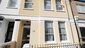 Un hilera de casas urbanas con el número 268 en la fachada, una puerta blanca y una cerca de hierro forjado negro.