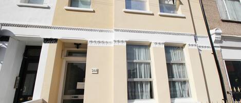 A row of townhouses with a number '268' on the facade, a white door, and a black wrought iron fence.