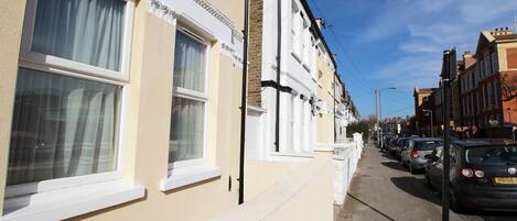 A row of terraced houses with white window frames and a clear blue sky.