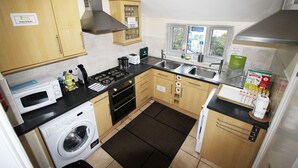 Cocina compacta con lavadora, estufa, microondas y ventana con vistas.