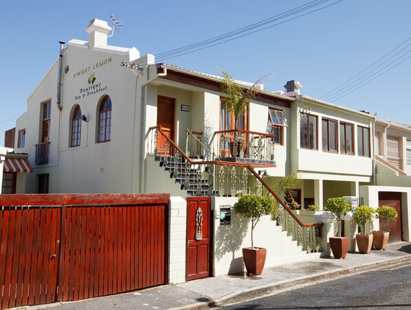 A two-story building with a balcony, a staircase, and a red gate.
