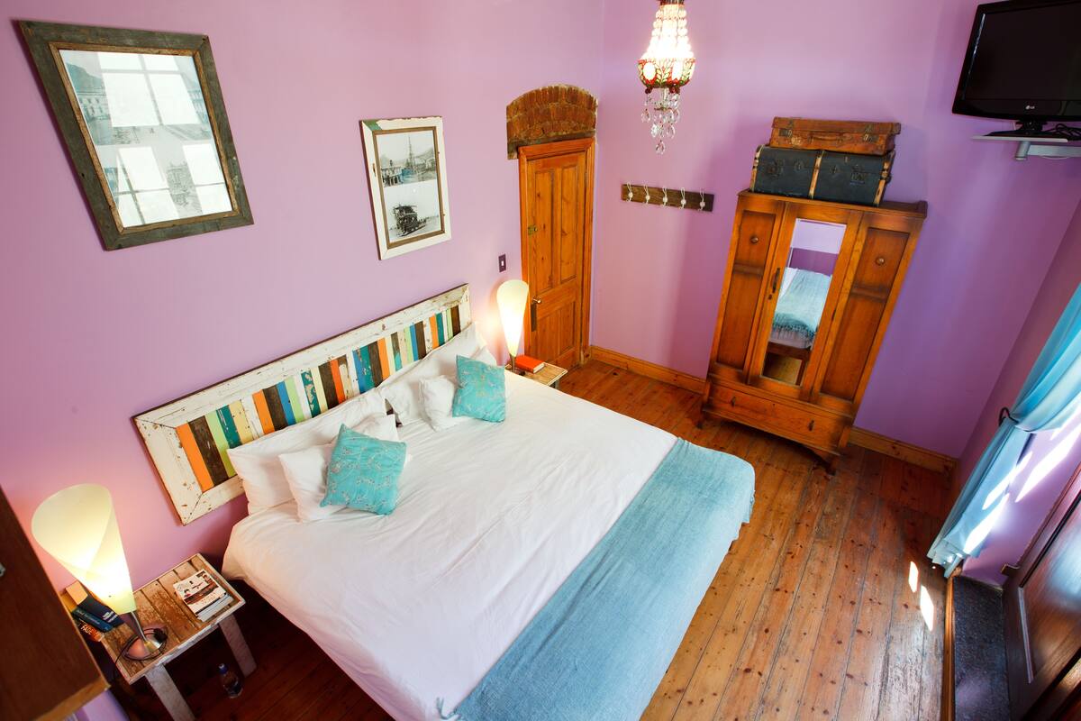 Un dormitorio con una cama grande, cabecera de madera y un aparador con maletas.