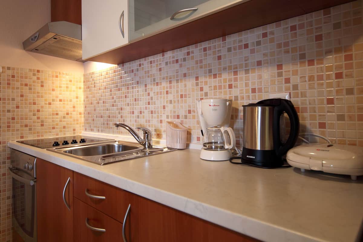 A kitchen with a stainless steel sink, a coffee maker, a kettle, and a toaster.