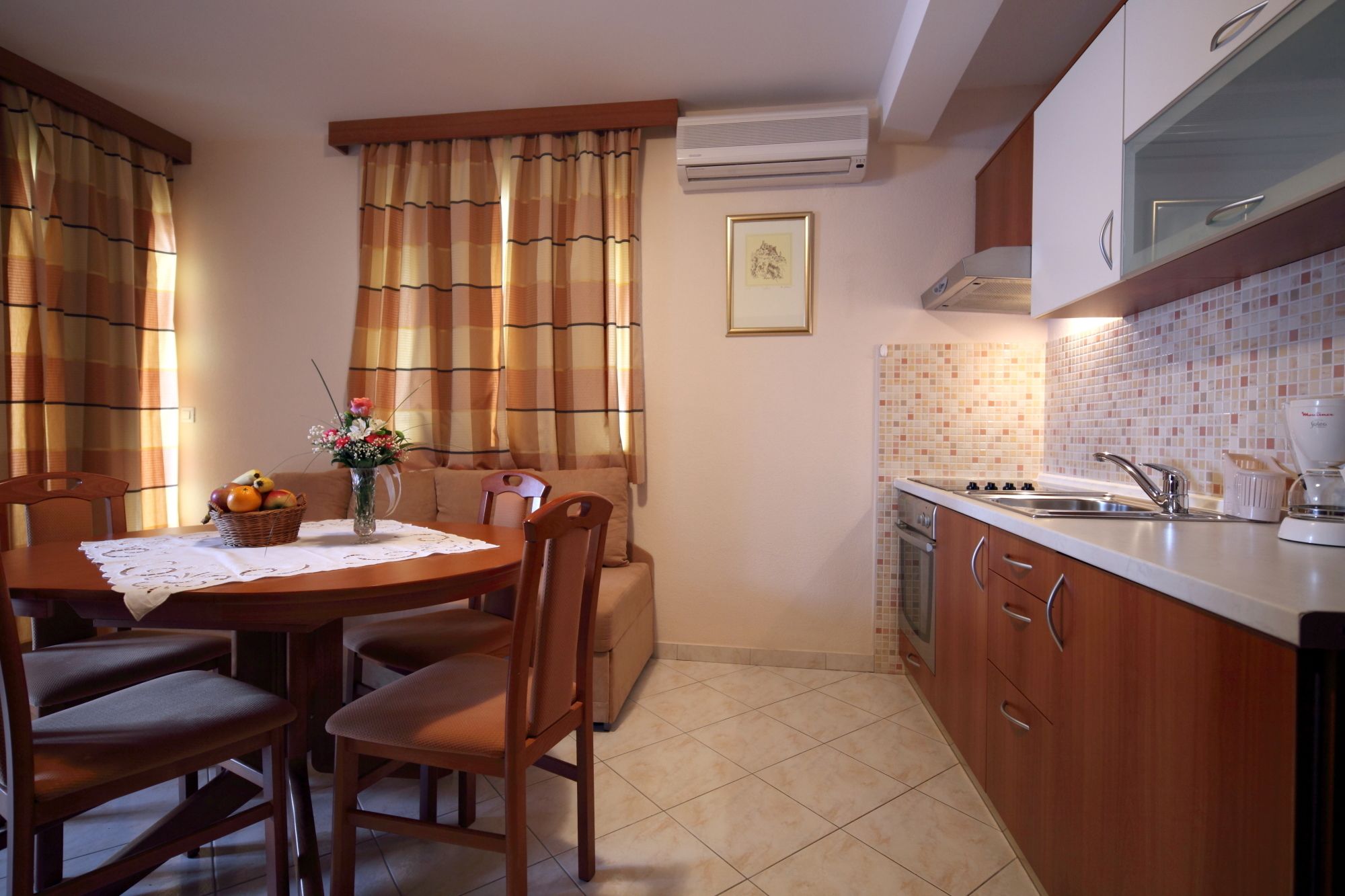 A compact kitchen with a dining area, featuring a tiled backsplash, wooden cabinets, and a built-in oven.