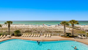 A swimming pool with lounge chairs and a view of the beach. - Azure Condominiums (Fort Walton Beach)