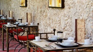 Een restaurant met stenen muren, houten tafels en rode stoelen.