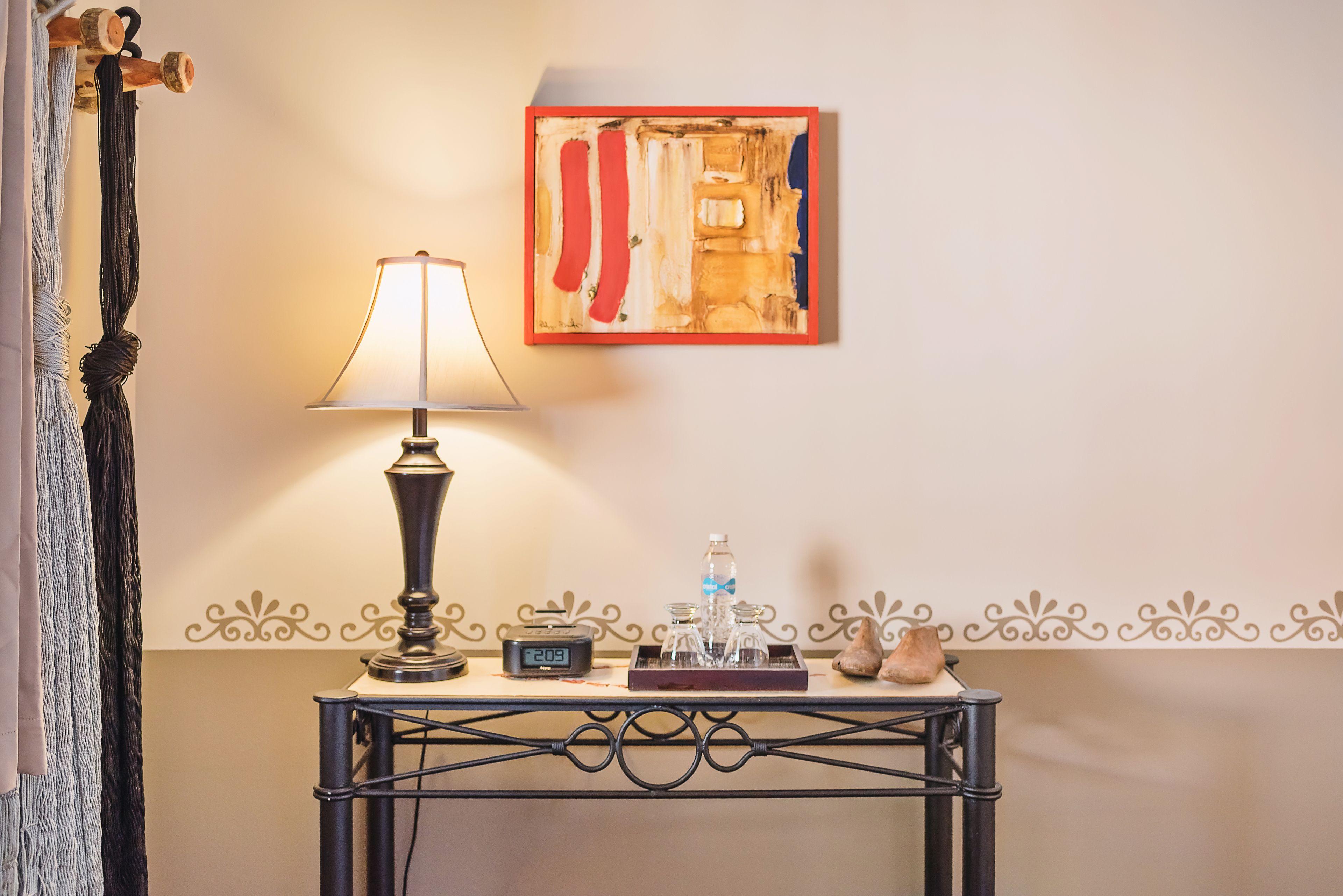 A table with a lamp, a clock, and a tray with bottles and glasses.