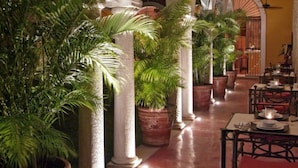 Een hotel lobby met zuilen, potplanten en tafels met stoelen.