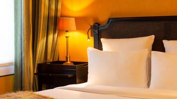Une chambre d’hôtel avec un lit, des oreillers, une table de chevet, une lampe et des rideaux.
