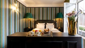 A hotel room with a bed, bedside lamps, a breakfast tray, and a window with a view. - New Hotel République (Paris)