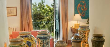 A display of pottery on a glass table in a room with a view of greenery outside.