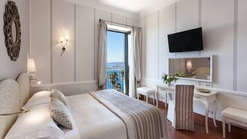 A hotel room with a bed, a desk, a chair, a TV, and a view of the city.
