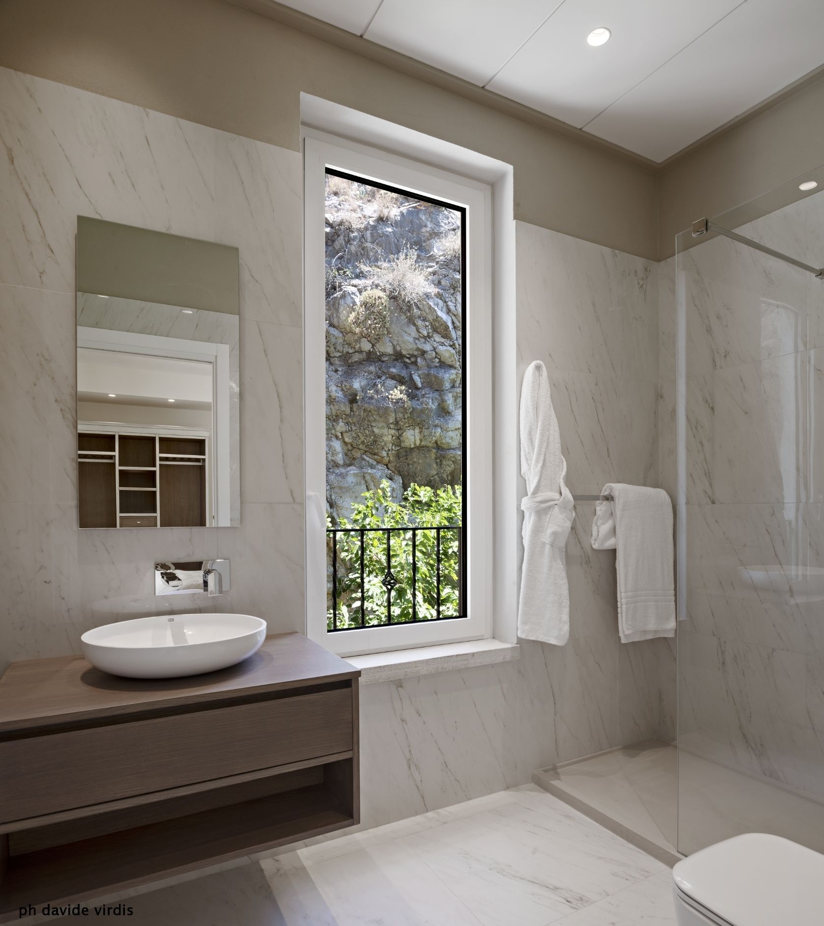 Un bagno moderno con un'ampia finestra, un lavandino, uno specchio e uno spazio doccia.