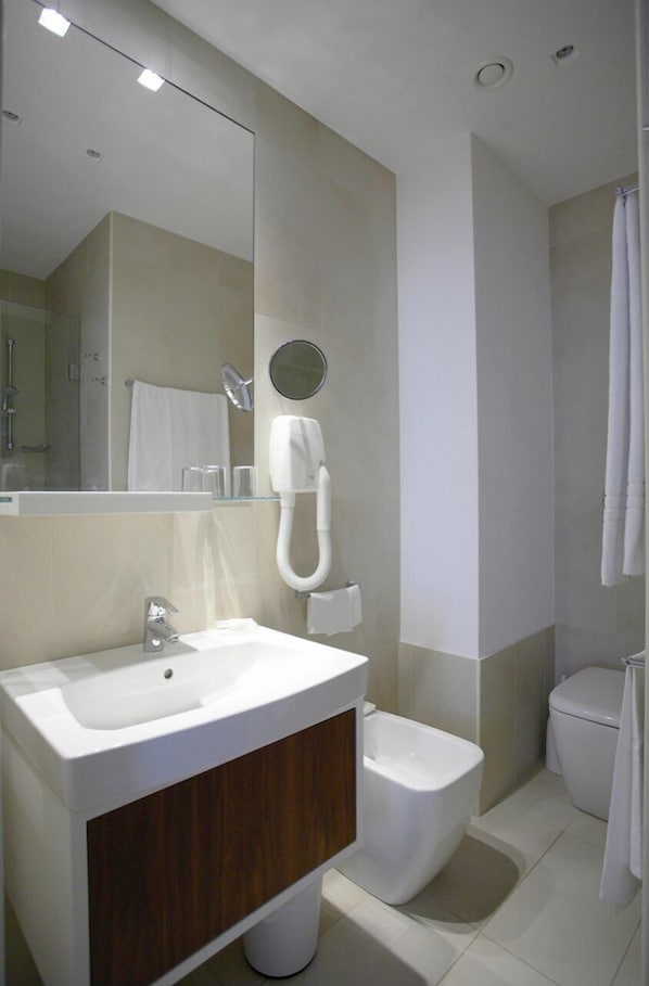 Un baño moderno con lavabo, espejo, inodoro y ducha.