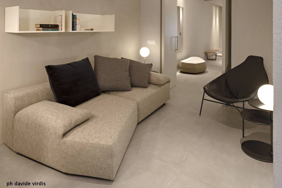 Een moderne woonkamer met een bank, een fauteuil, een ronde tafel en een boekenkast.