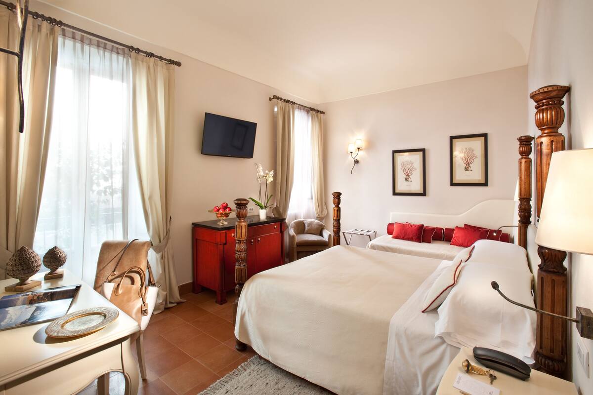 Een hotelkamer met twee bedden, een bureau met stoel, een televisie en kunst aan de muur.