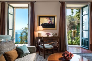 A room with a view of the sea, a desk with a lamp, a chair, and a table with a vase of flowers. - Hotel Villa Belvedere (Taormina)
