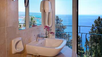 A bathroom with a white sink, a hand dryer, and a flower vase.