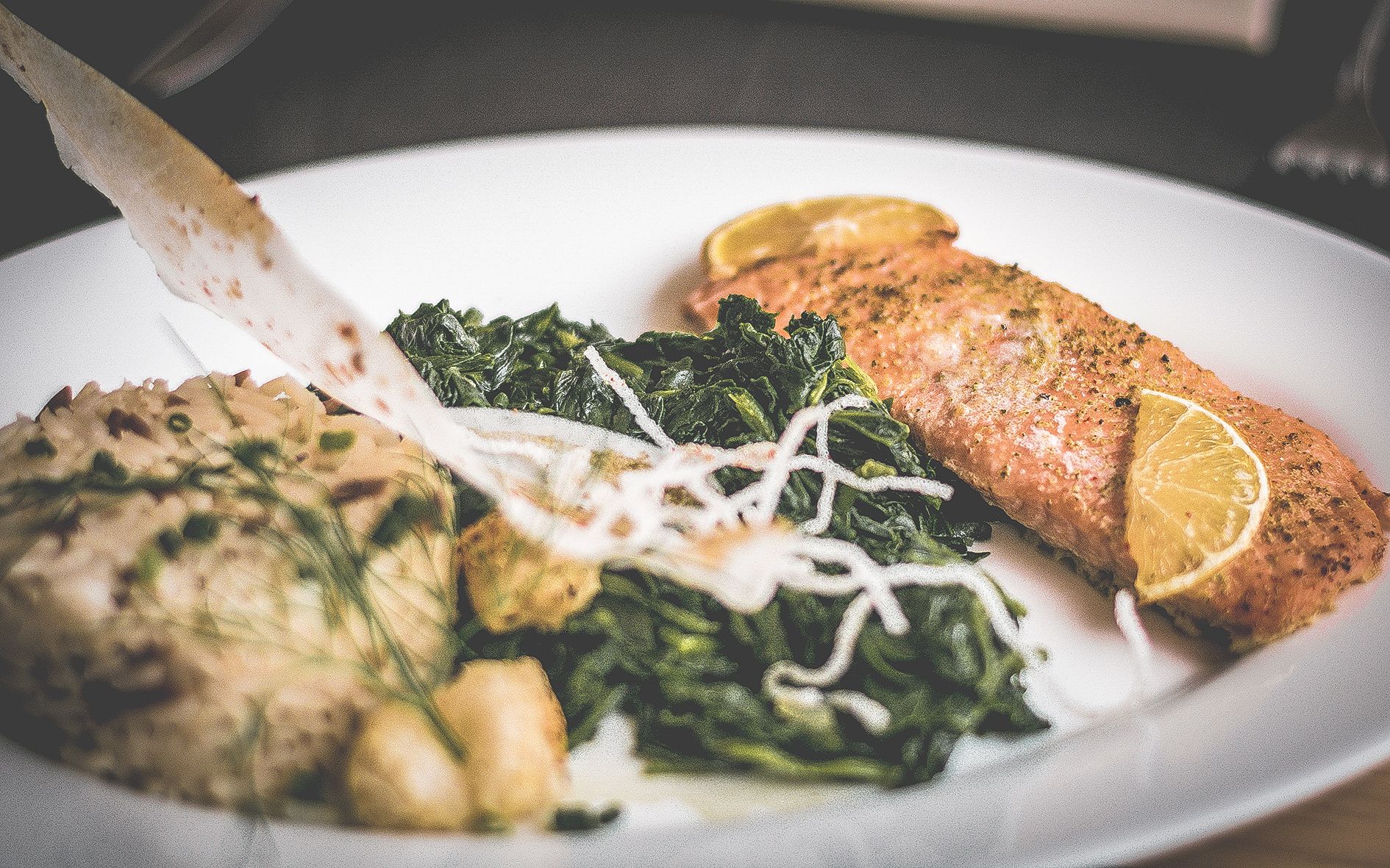 Ein Teller mit Lachs, Hähnchen und einem Beilagengemüse.