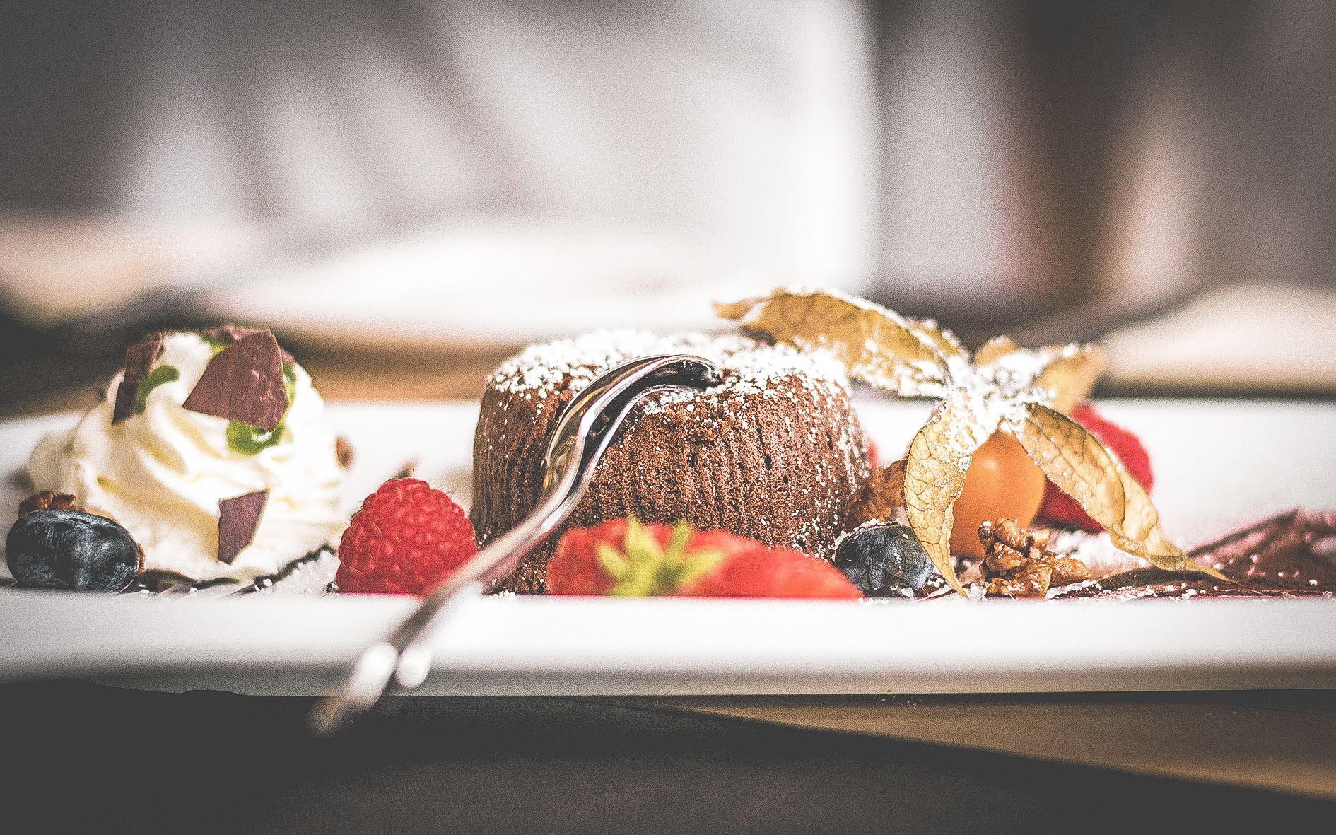 A dessert plate with a chocolate cake, strawberries, blueberries, whipped cream, and chocolate shavings.