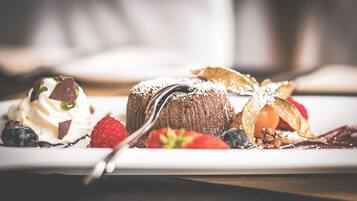 A dessert plate with a chocolate cake, strawberries, blueberries, whipped cream, and chocolate shavings.