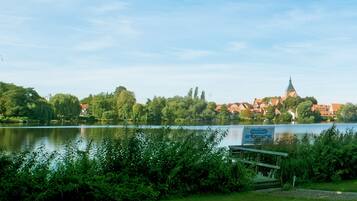A lakeside view with a restaurant sign, greenery, and buildings in the background.