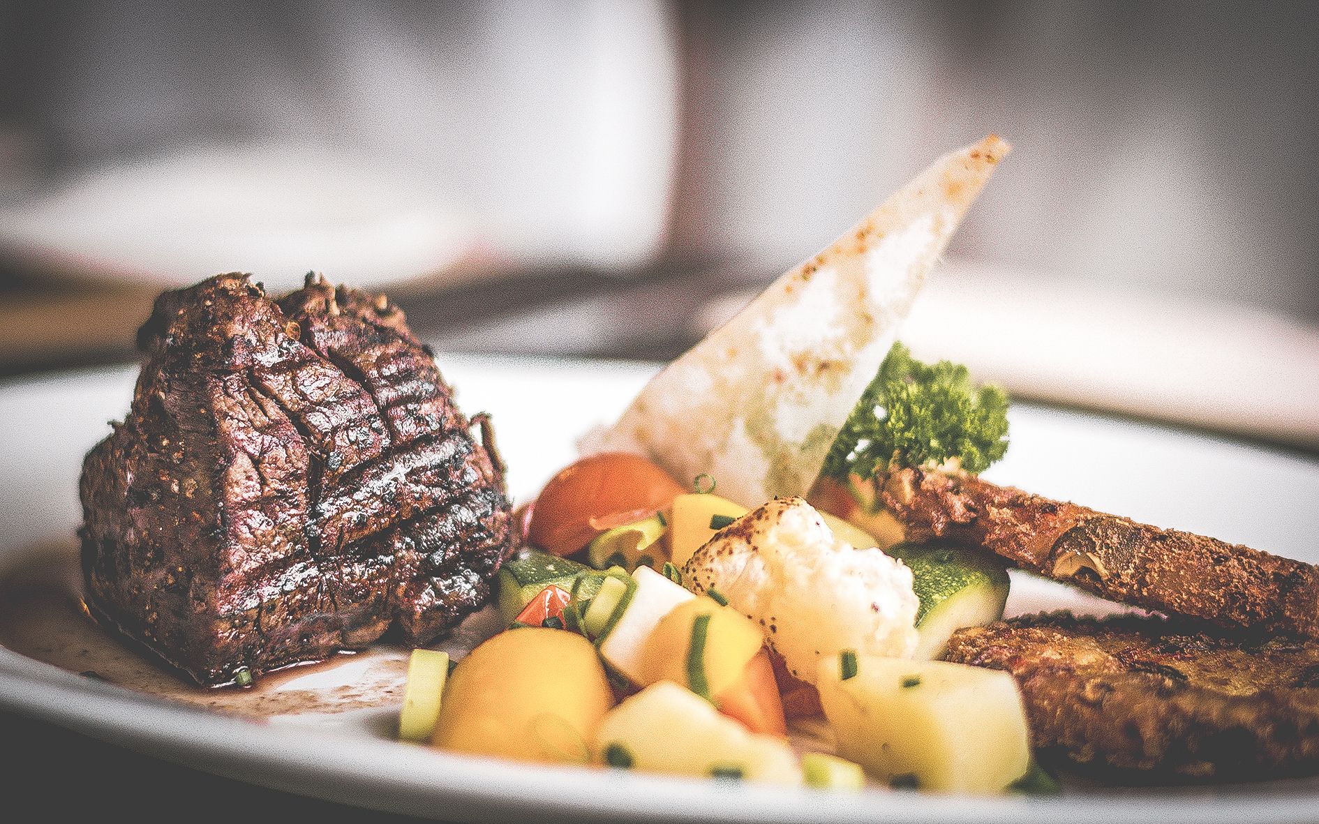 Un plato con bistec a la parrilla, verduras y una porción de pan plano.
