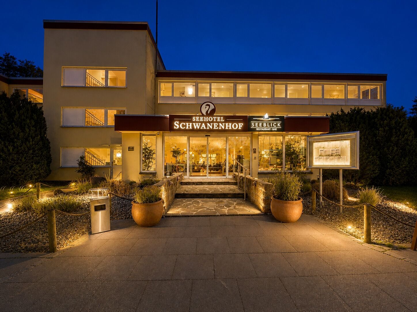 Entrada de un hotel con un letrero que indica Seehotel Schwabenhof y el restaurante-bar Seeblick.