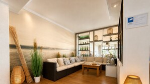 A living room with a sofa, a coffee table, and a bookshelf. - Seehotel Schwanenhof (Moelln)